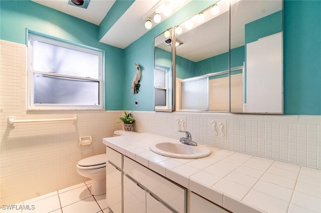 full bath with toilet, a shower with door, tile patterned floors, vanity, and tile walls