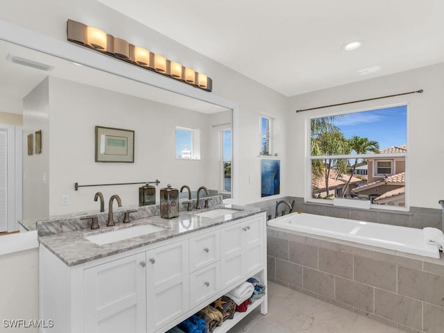 bathroom with plenty of natural light, vanity, and tiled bath