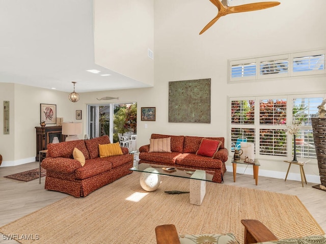 living room featuring a high ceiling, ceiling fan, and light hardwood / wood-style floors