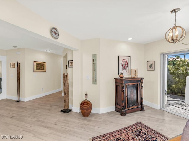 corridor with a notable chandelier and light hardwood / wood-style floors