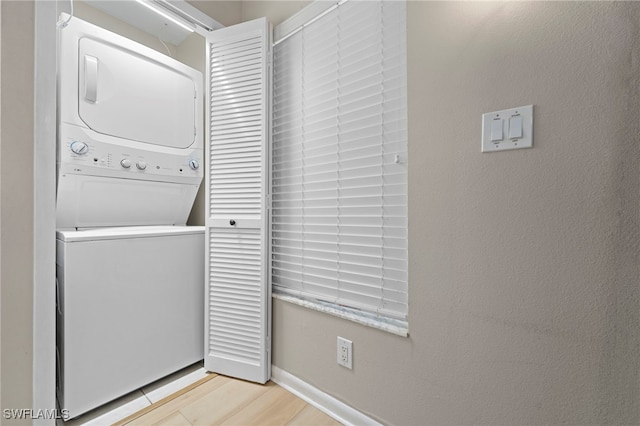 clothes washing area featuring stacked washing maching and dryer and light hardwood / wood-style floors