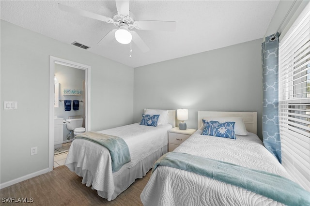 bedroom with ceiling fan, ensuite bath, and a textured ceiling