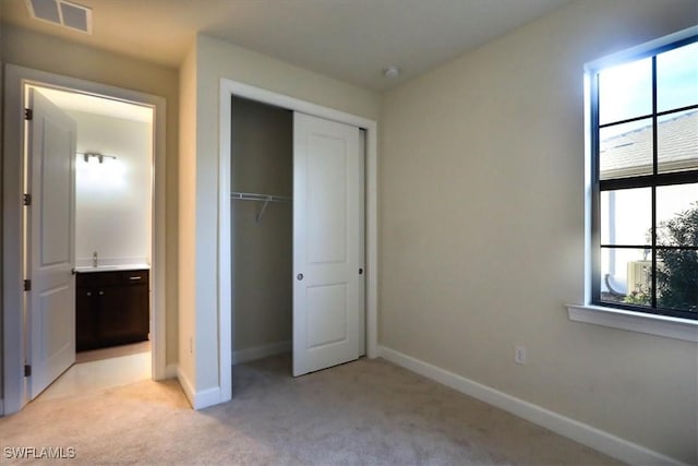 unfurnished bedroom with a closet and light colored carpet