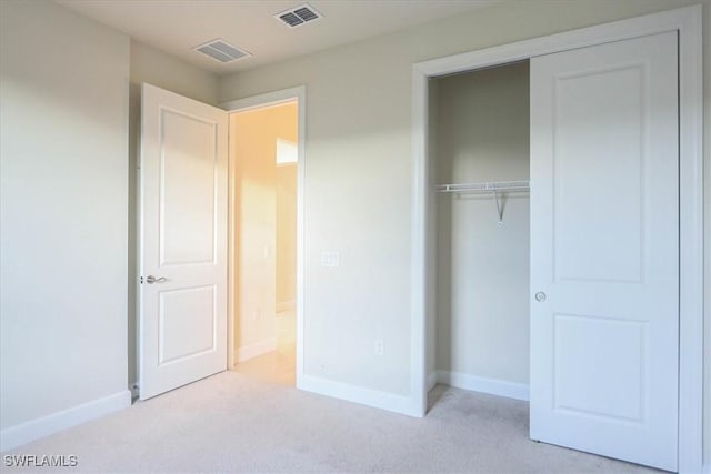 unfurnished bedroom with light carpet and a closet