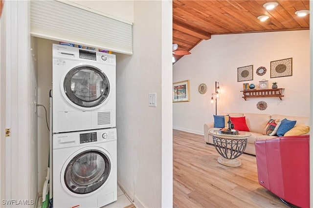 laundry area featuring wooden ceiling, stacked washer and dryer, laundry area, wood finished floors, and baseboards