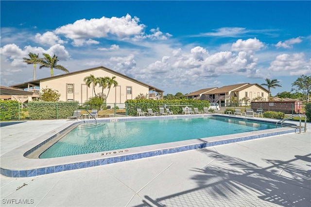 pool with a residential view, fence, and a patio