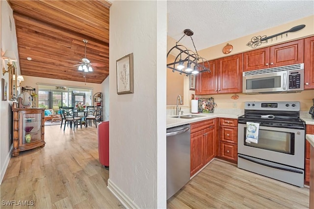 kitchen featuring light wood finished floors, decorative light fixtures, stainless steel appliances, light countertops, and a sink