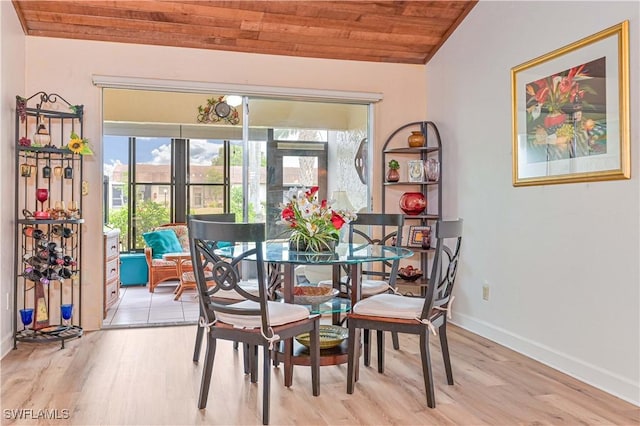 dining space featuring lofted ceiling, wooden ceiling, baseboards, and light wood finished floors