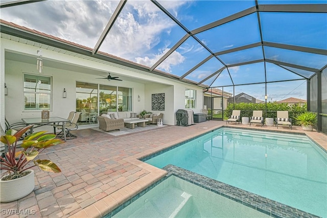 view of swimming pool with a pool with connected hot tub, a ceiling fan, a patio area, glass enclosure, and an outdoor living space