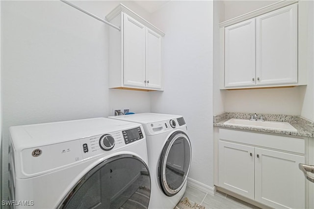 laundry room featuring cabinet space, baseboards, a sink, and independent washer and dryer