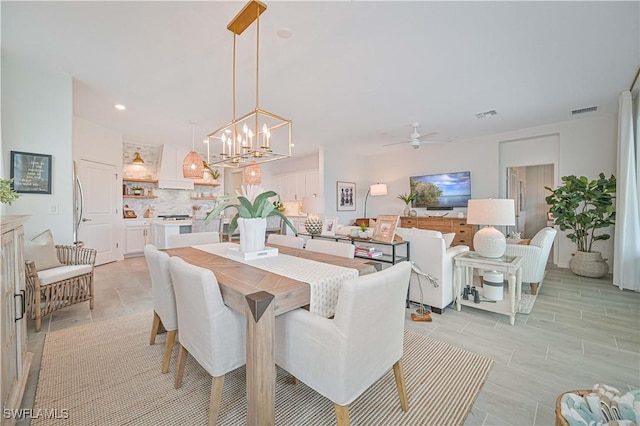 dining space with ceiling fan with notable chandelier and visible vents