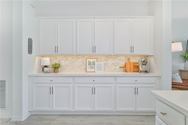 interior space with white cabinets, light countertops, and backsplash