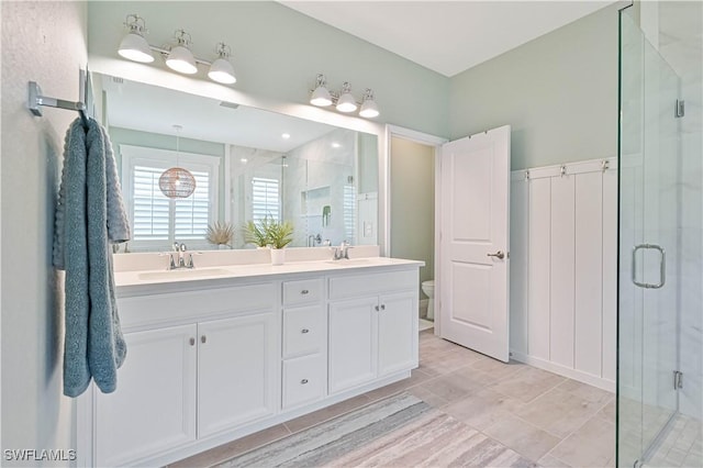 full bathroom with a sink, double vanity, a shower stall, and toilet