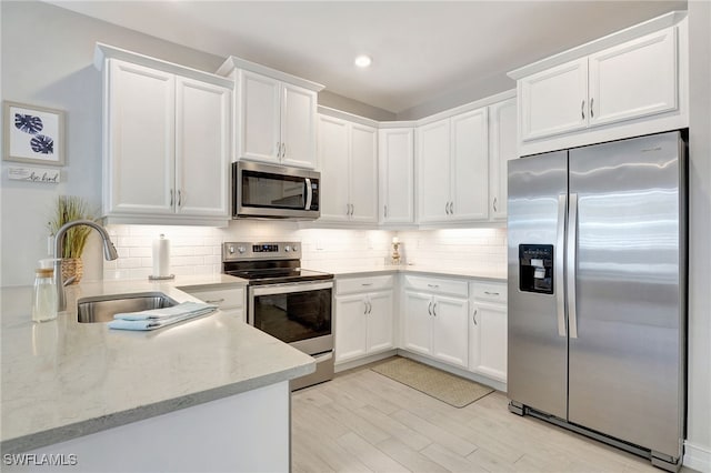 kitchen with sink, stainless steel appliances, light stone countertops, and white cabinets