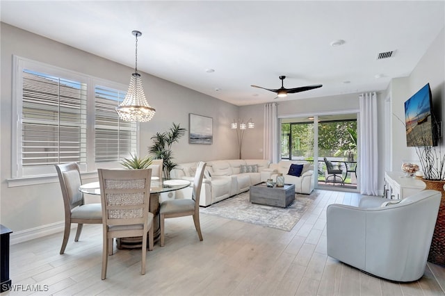 dining space featuring ceiling fan with notable chandelier and light hardwood / wood-style flooring