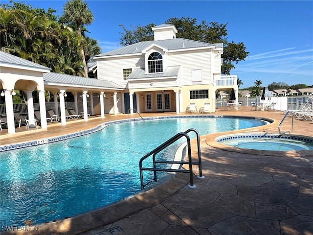 community pool featuring a patio, french doors, fence, and a hot tub