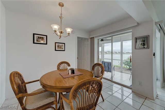 dining space featuring a water view, an inviting chandelier, and light tile patterned floors