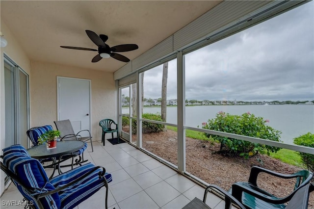 sunroom / solarium with ceiling fan and a water view