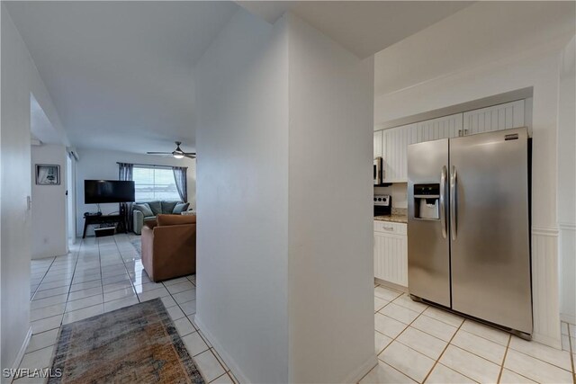 kitchen with open floor plan, appliances with stainless steel finishes, light tile patterned floors, and white cabinetry