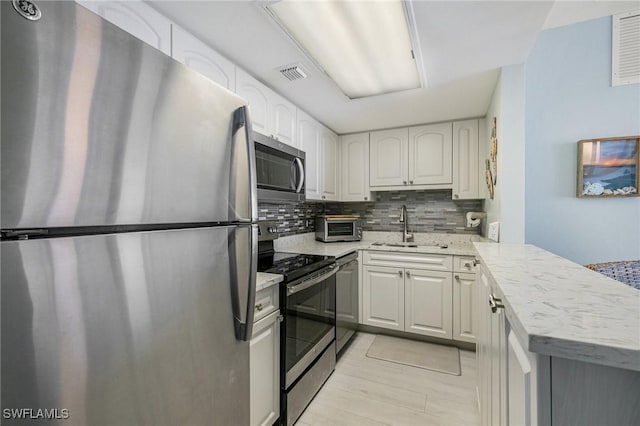 180 Seaview Ct Unit 911, Marco Island, FL 34145 - kitchen featuring appliances with stainless steel finishes, a sink, backsplash, white cabinets, and a peninsula