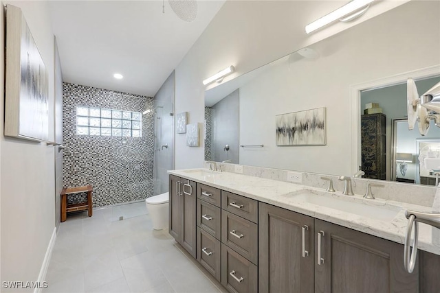 bathroom featuring tile patterned floors, a tile shower, vanity, and toilet