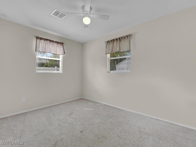 carpeted spare room featuring visible vents, ceiling fan, and baseboards