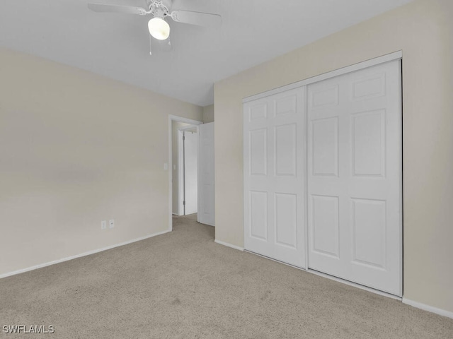 unfurnished bedroom with a closet, light carpet, ceiling fan, and baseboards