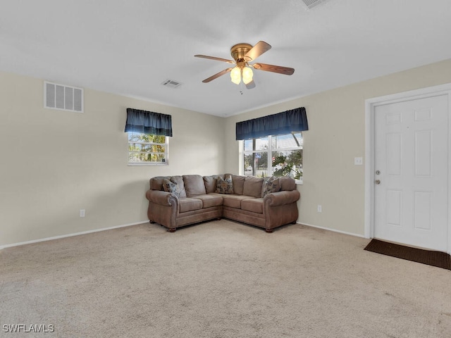 carpeted living room with ceiling fan, visible vents, and a wealth of natural light