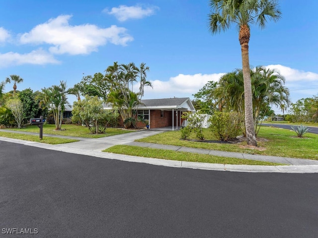 view of front of property with an attached carport, concrete driveway, and a front lawn