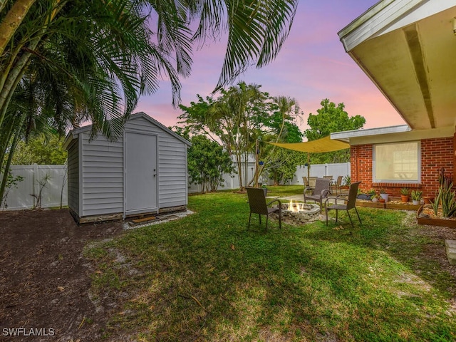 view of yard with a fire pit, a storage unit, an outdoor structure, and a fenced backyard