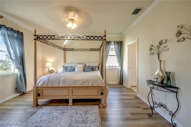 bedroom with ornamental molding, wood finished floors, and visible vents