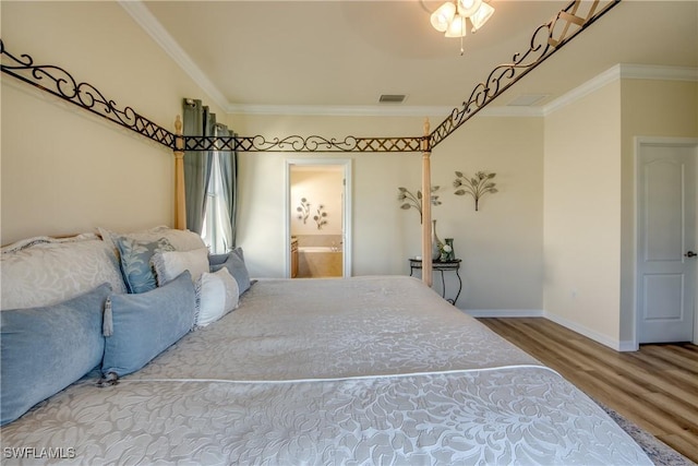 bedroom featuring visible vents, baseboards, connected bathroom, wood finished floors, and crown molding