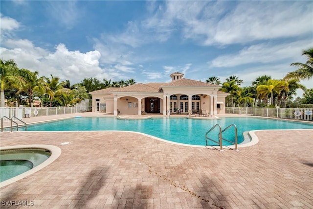 pool featuring fence, a hot tub, and a patio