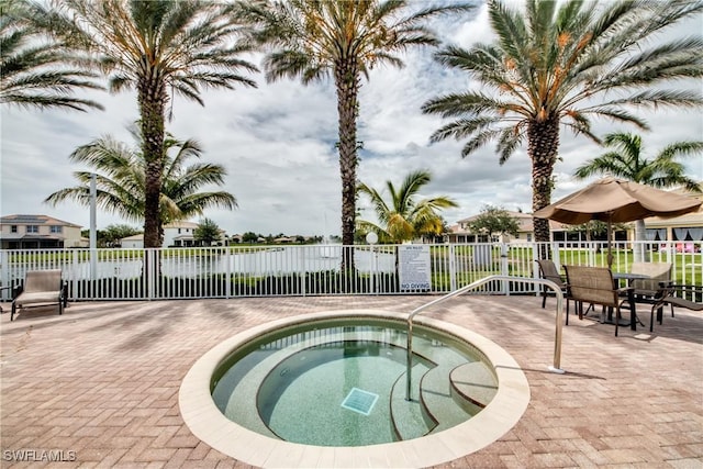 view of pool with a community hot tub, a patio, and fence