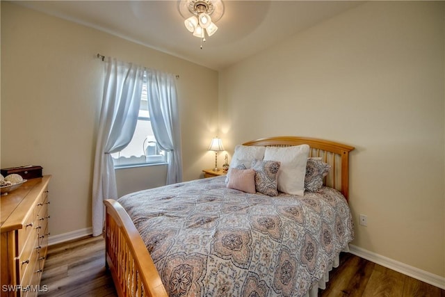 bedroom with dark wood-type flooring, vaulted ceiling, and baseboards