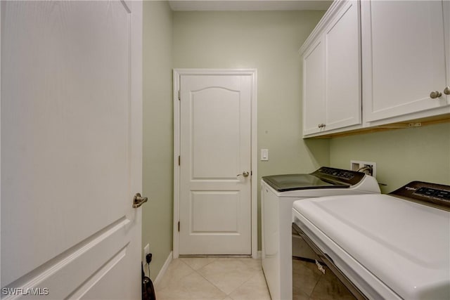 clothes washing area with cabinet space, light tile patterned floors, baseboards, and washer and clothes dryer