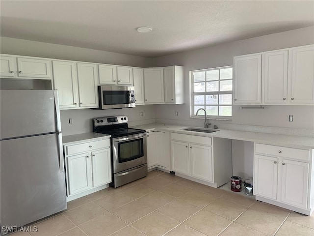 kitchen with sink, white cabinets, stainless steel appliances, and light tile patterned floors