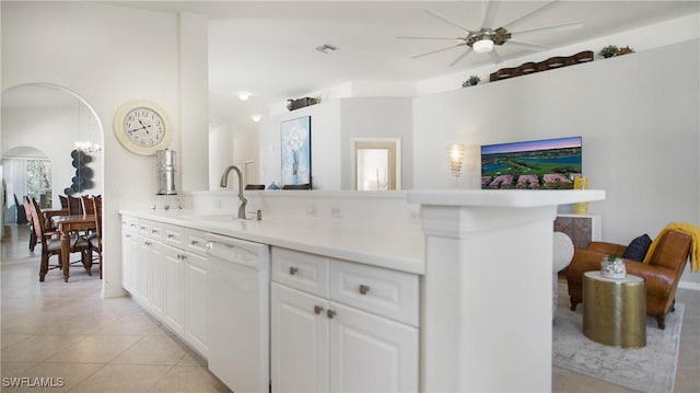 kitchen featuring arched walkways, light countertops, white cabinets, white dishwasher, and a sink