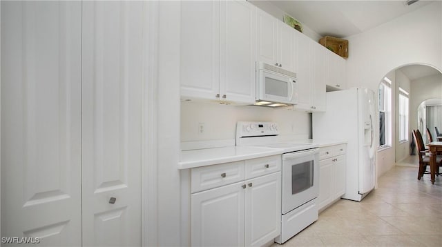 kitchen with white appliances, arched walkways, white cabinets, light countertops, and light tile patterned flooring