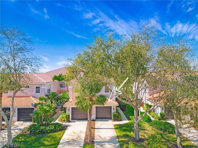 view of front of home featuring a garage, concrete driveway, a tile roof, and stucco siding