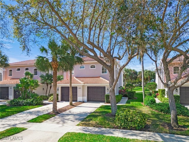 view of front facade featuring concrete driveway, a tiled roof, a front lawn, and stucco siding