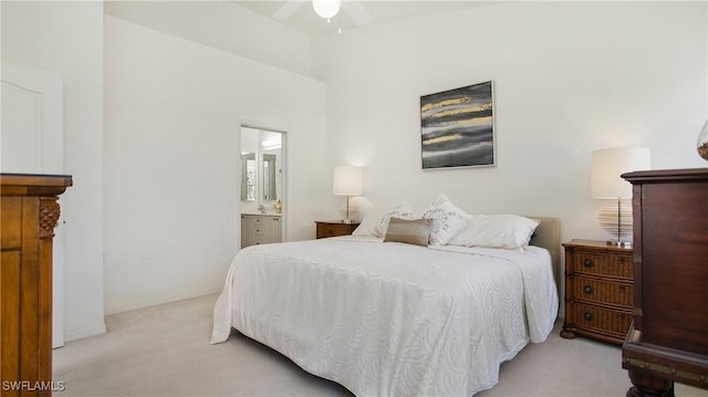 bedroom with baseboards, light carpet, and ensuite bath