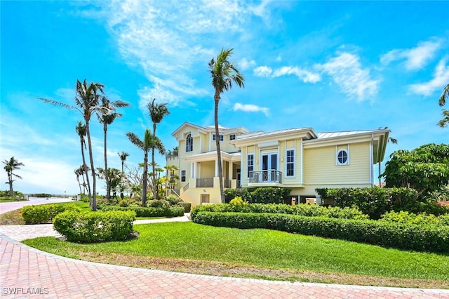 view of front of house featuring a front lawn, french doors, and a balcony