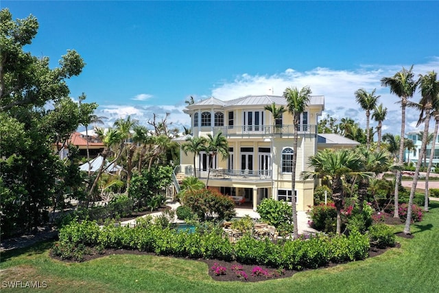 rear view of house featuring french doors, a yard, and a balcony