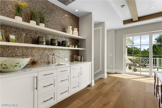 bar with visible vents, beam ceiling, a sink, hardwood / wood-style flooring, and tasteful backsplash