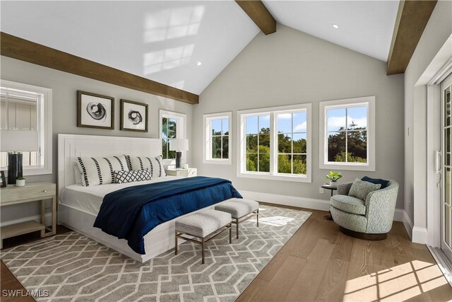 bedroom with beamed ceiling, wood finished floors, baseboards, and high vaulted ceiling