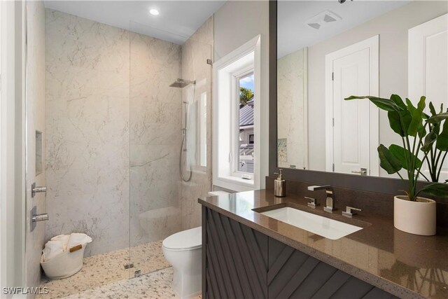 bathroom featuring toilet, vanity, and a walk in shower