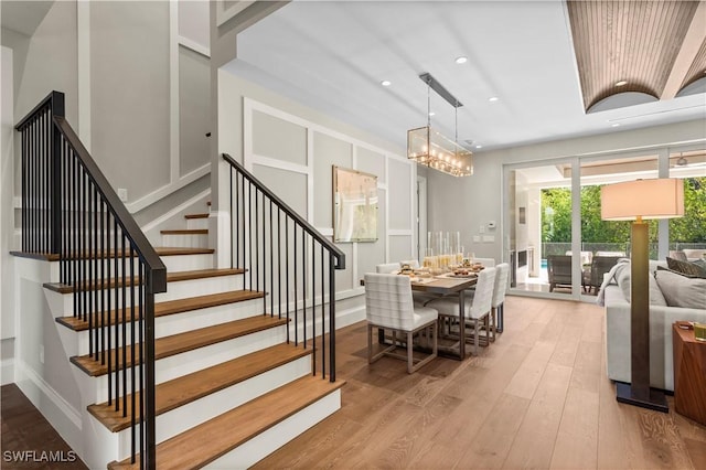 dining area featuring baseboards, stairway, recessed lighting, wood finished floors, and a notable chandelier