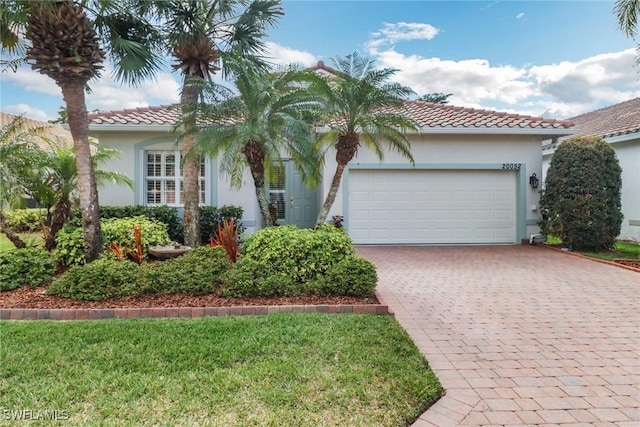 view of front of home with a tiled roof, decorative driveway, an attached garage, and stucco siding