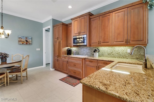 kitchen featuring hanging light fixtures, stainless steel microwave, a sink, and brown cabinets